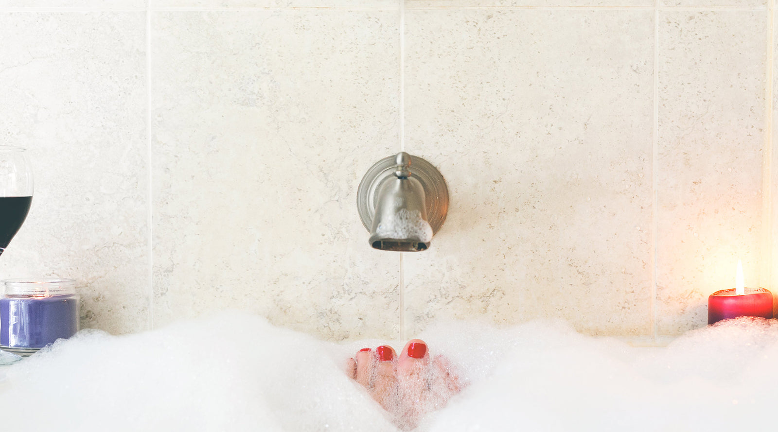 Red-painted toe sticking out of bubble bath underneath faucet | Nikki Darling Australia